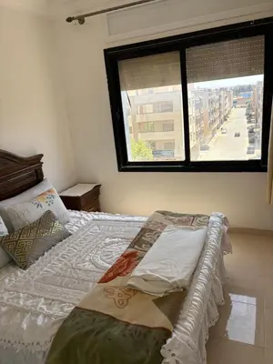 a bedroom with a bed and a window with a street at Résidence Oslo in Khemisset