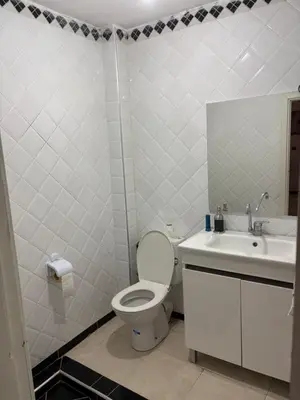 a white bathroom with a toilet and a sink at Résidence Oslo in Khemisset