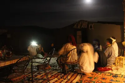 a group of people sitting in a room at night at chez zakaria luxury tent camp merzouga in Erfoud
