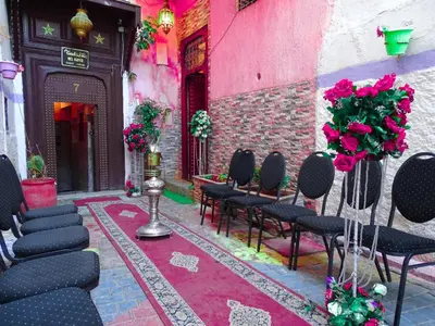 a room with black chairs and a pink wall at el habib in Fès
