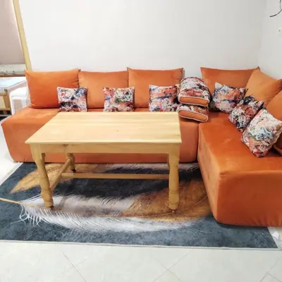 an orange couch with pillows and a coffee table at Maison d'hôte Najah 2 in Khenifra