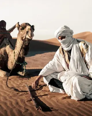 a camel and a person sitting in the desert at Serenity desert luxury Camp in Merzouga