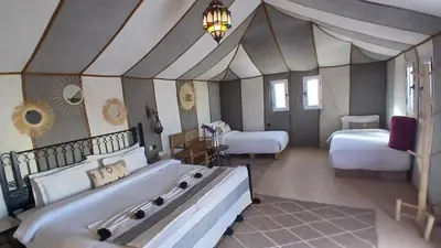 a large bedroom with two beds and a chandelier at Serenity desert luxury Camp in Merzouga