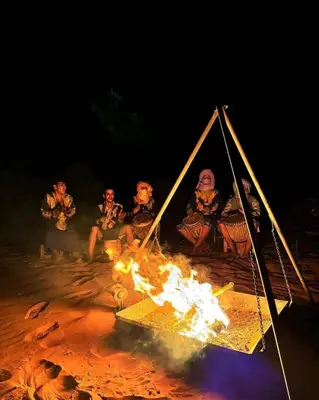 a group of people sitting around a fire at Serenity desert luxury Camp in Merzouga