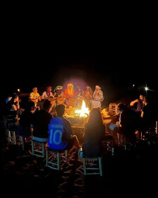 a group of people sitting around a fire at night at Luxury Merzouga stars camp in Merzouga