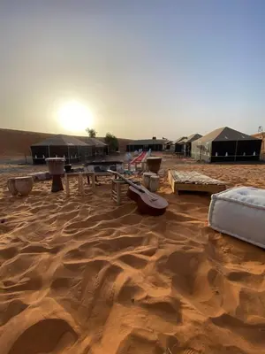 a desert with tents and a bed in the sand at Luxury Merzouga stars camp in Merzouga