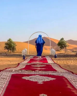 a person walking on a red carpet in the desert at Merzougadreamcamp in Merzouga