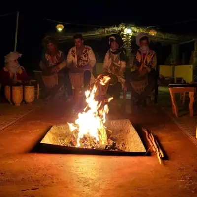 a group of people sitting around a fire at Merzougadreamcamp in Merzouga