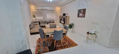 a dining room and living room with a table and a couch at Appartement de charme in Fès