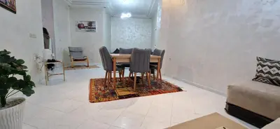 a dining room with a table and chairs on a rug at Appartement de charme in Fès