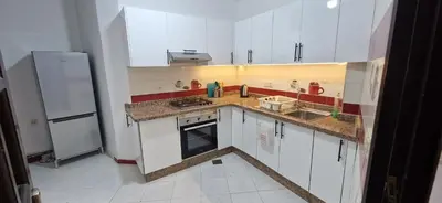 a small kitchen with white cabinets and a refrigerator at Cozy apartment in Fès