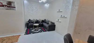 a living room with black leather couches and a table at Cozy apartment in Fès