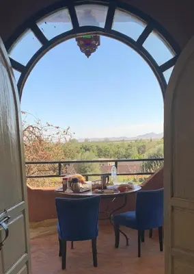 a room with a table and chairs on a balcony at Riad Belgika Marrakech in Ourika