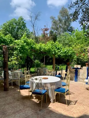 a table and chairs with a white table and some trees at Riad Belgika Marrakech in Ourika