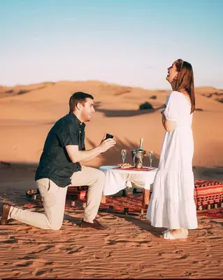 a man and a woman sitting at a table in the desert at Merzouga Berber Luxury Camp in Merzouga