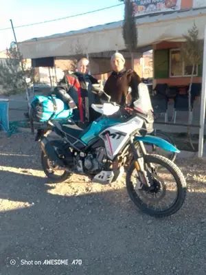 two men are standing next to a motorcycle at Ait hani in Tinerhir