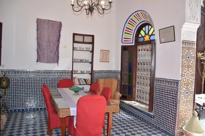 a dining room with a table and red chairs at Dar Al Batoul in Fès