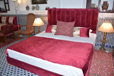 a bedroom with a large bed with red sheets and pillows at Dar Al Batoul in Fès