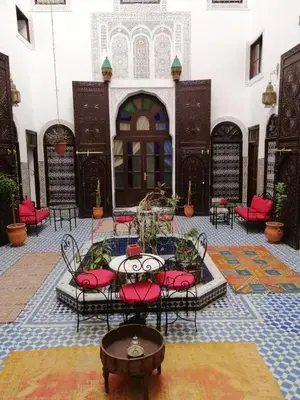 a courtyard with red chairs and a table in a building at Dar Al Batoul in Fès