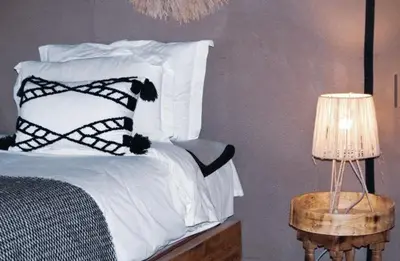 a bed with black and white pillows and a lamp at Merzouga Queen Luxury Camp in Merzouga