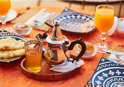 a table with a tea kettle and some drinks at Merzouga Queen Luxury Camp in Merzouga