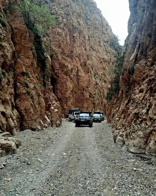 a group of cars parked on a dirt road in a canyon at Gîte flilou in Midelt