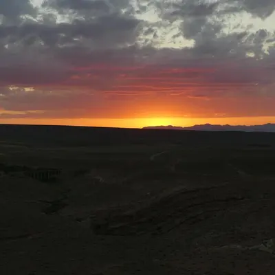 a sunset in the desert with the sun setting at Gîte flilou in Midelt