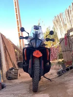 a motorcycle parked on a dirt road next to a fence at Gîte flilou in Midelt
