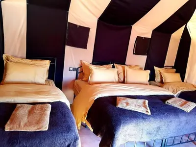 a bedroom with two beds in a tent at Merzouga camp activités in Merzouga