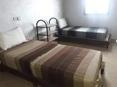 a bedroom with two beds and a chair in it at Merzouga camp activités in Merzouga