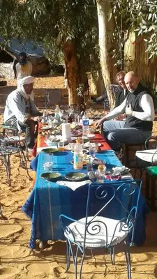 a group of people sitting around a blue table at Merzouga camp activités in Merzouga