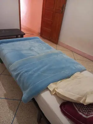 a bed with a blue blanket on top of it at Chez La FAMILLE in Kalaat MGouna