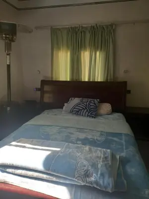 a bed with a blue comforter and a window at Chez La FAMILLE in Kalaat MGouna