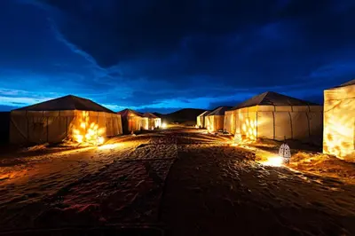 a row of tents at night with lights at Crystaldunes Luxurycampe in Merzouga