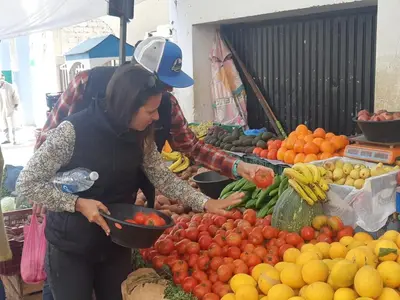 two women standing in front of a fruit stand at Fès Dar medina in Fès