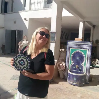 a woman standing in front of a display of art at Fès Dar medina in Fès