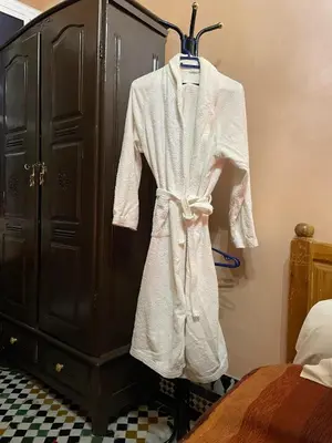 a robe hanging on a rack next to a bed at Riad Famille Drissi Kaitouni in Fès