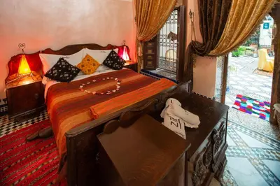 a bedroom with a bed and a dresser and a window at Riad Famille Drissi Kaitouni in Fès