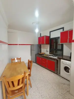 a kitchen with red cabinets and a wooden table and chairs at appartement splendid au centre ville in Fès