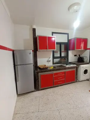 a kitchen with red cabinets and a refrigerator at appartement splendid au centre ville in Fès