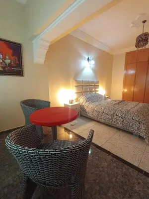 a bedroom with a bed and a red table and chairs at appartement splendid au centre ville in Fès