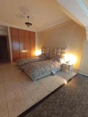 a bedroom with two beds and a table with lights at appartement splendid au centre ville in Fès