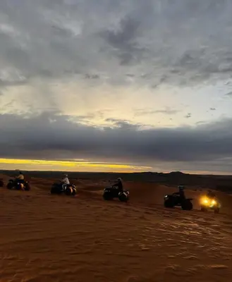 a group of people riding motorcycles in the desert at Moroccco Desert Luxury Tents in Merzouga