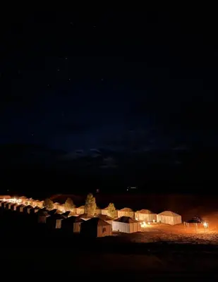 a row of houses lit up at night at Moroccco Desert Luxury Tents in Merzouga
