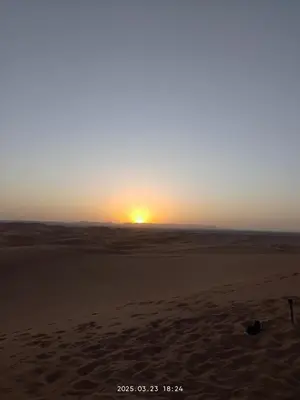 a sunset in the desert with the sun setting at Moroccco Desert Luxury Tents in Merzouga
