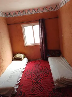 a small room with two beds and a window at gite Imouzar in Iabassene