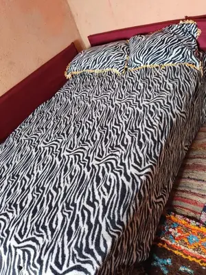 a bed with a zebra print comforter on it at gite Imouzar in Iabassene