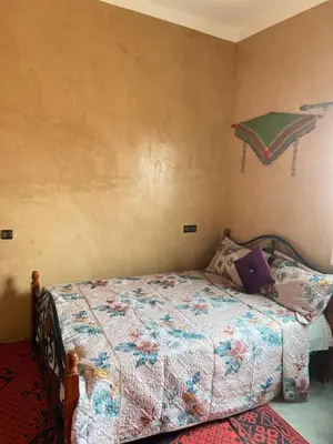 a bedroom with a bed and an umbrella on the wall at Auberge camping ouadjou in Nkob
