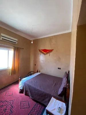 a bedroom with a bed and a red rug at Auberge camping ouadjou in Nkob