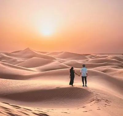 a couple walking through the desert at sunset at Malak Luxury Camp in Merzouga
